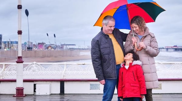 Senior couple with grandchild under umbrella