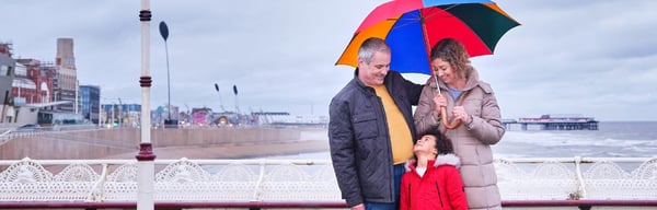 Senior couple over 50 holding umbrella by the sea